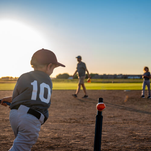 Caucasian boy with baseball bat at home plateswinging at ball o